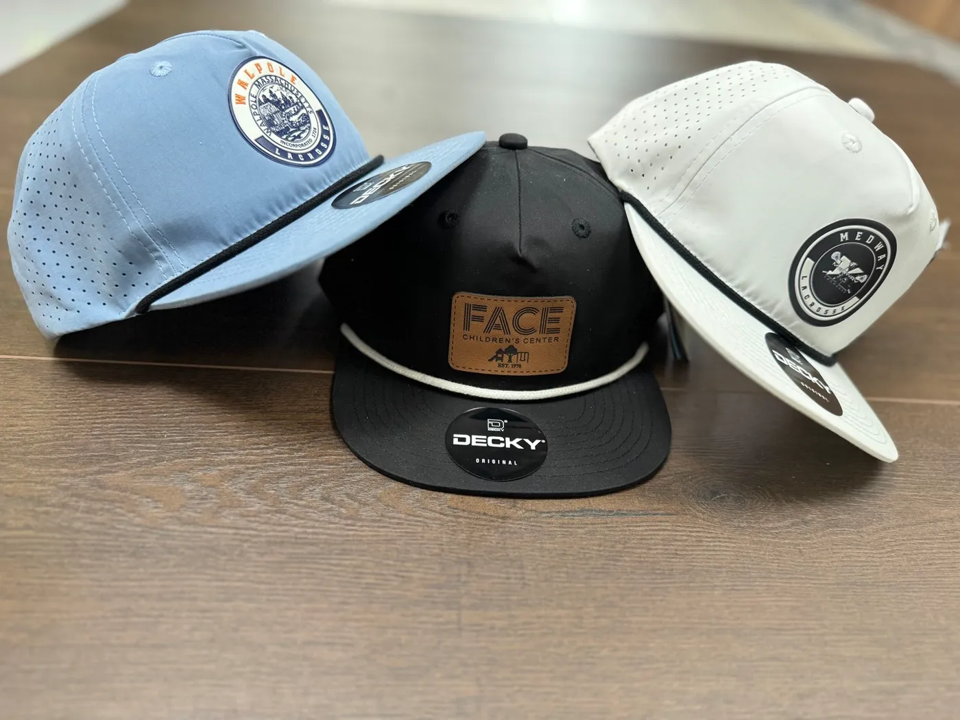 Three custom embroidered hats made for Walpole Lacrosse, Medway Lacrosse, and FACE Children's Center